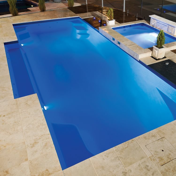 Rectangular fibreglass pool with a matching spa on travertine paving